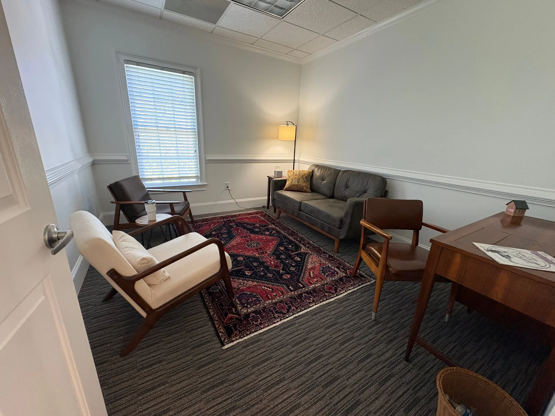 Therapy office at The Community with a sofa, armchairs and a red rug.